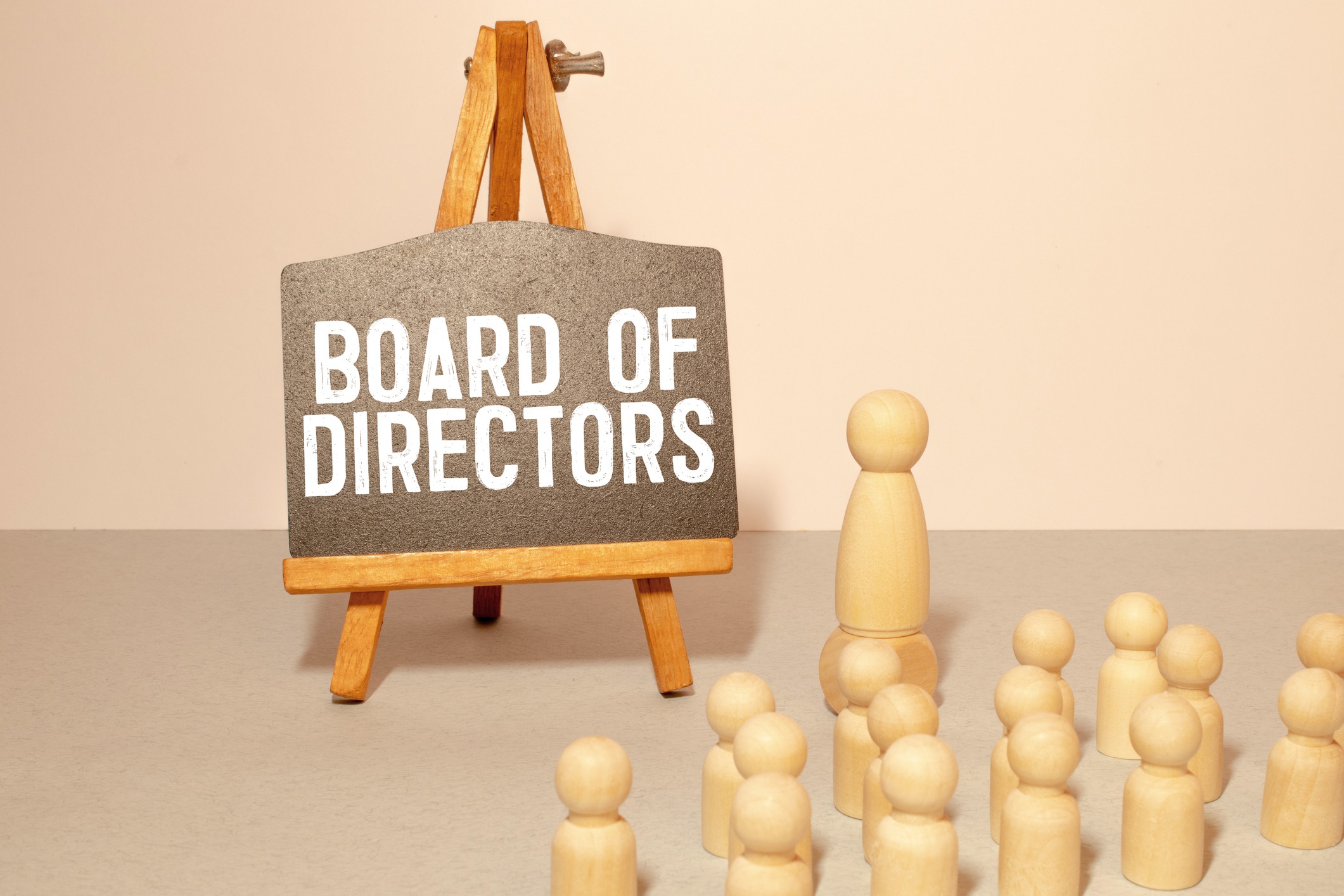 Photo of wooden figures standing in front of an easel and chalkboard with Board of Directors written on it