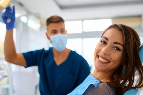 Young happy woman during teeth check-up at dental clinic looking at camera.