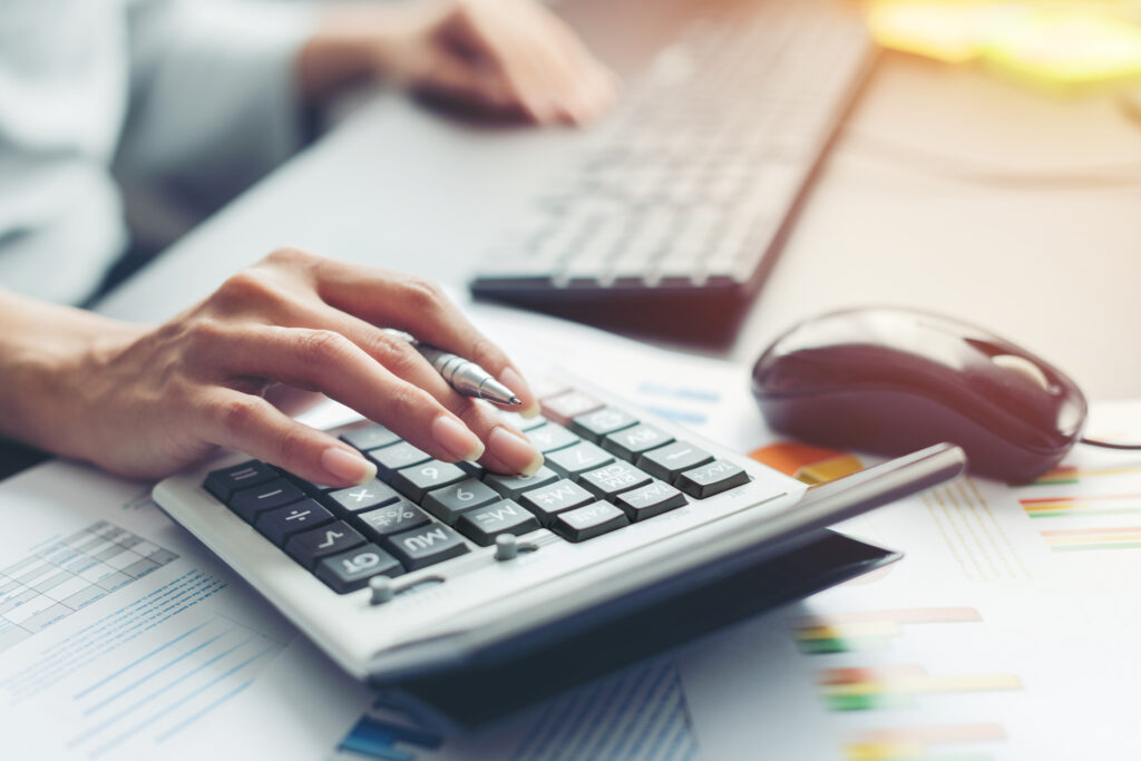 A photo of a close up hand making calculations on a calculator