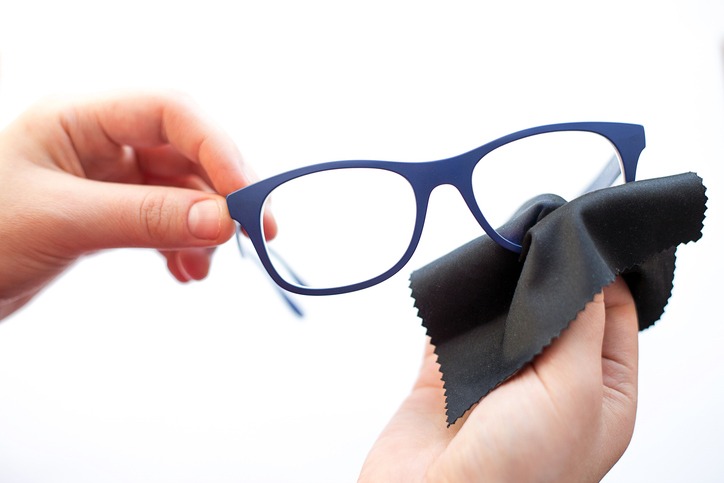 Female hands are wiping spectacles with a microfiber fabric