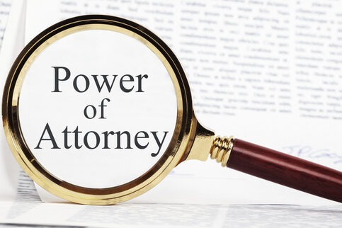 Power of Attorney Concept - paperwork representing a Power of Attorney, with a magnifying glass over, highlighting Power of Attorney.