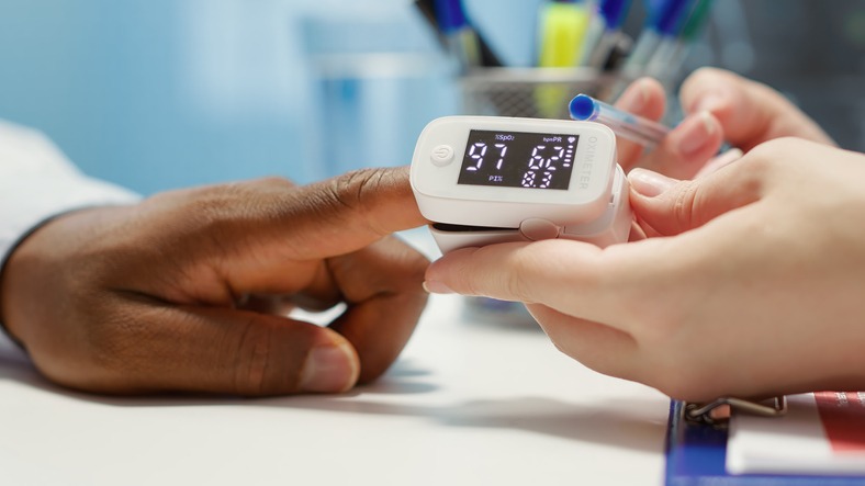 A patient receiving a pulse oximetry test from a medical professional