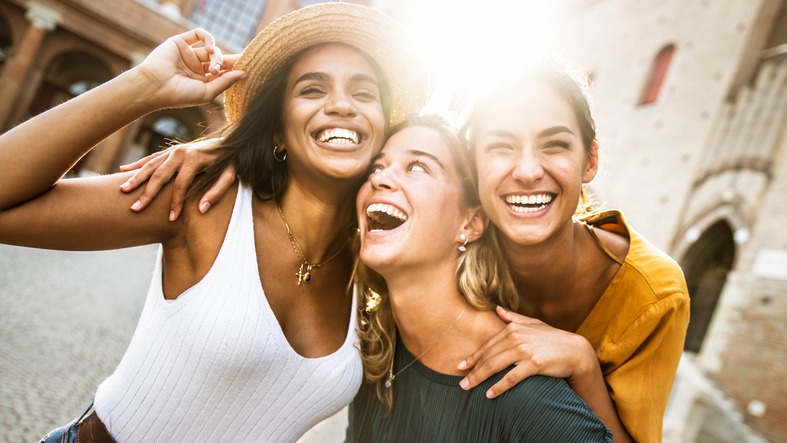 Three young multiracial women having fun on city street outdoors