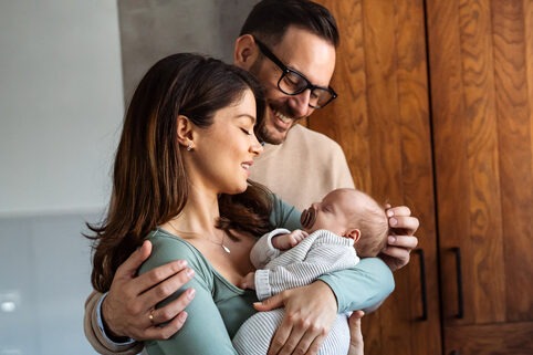 Portrait of young happy man and woman holding a newborn baby
