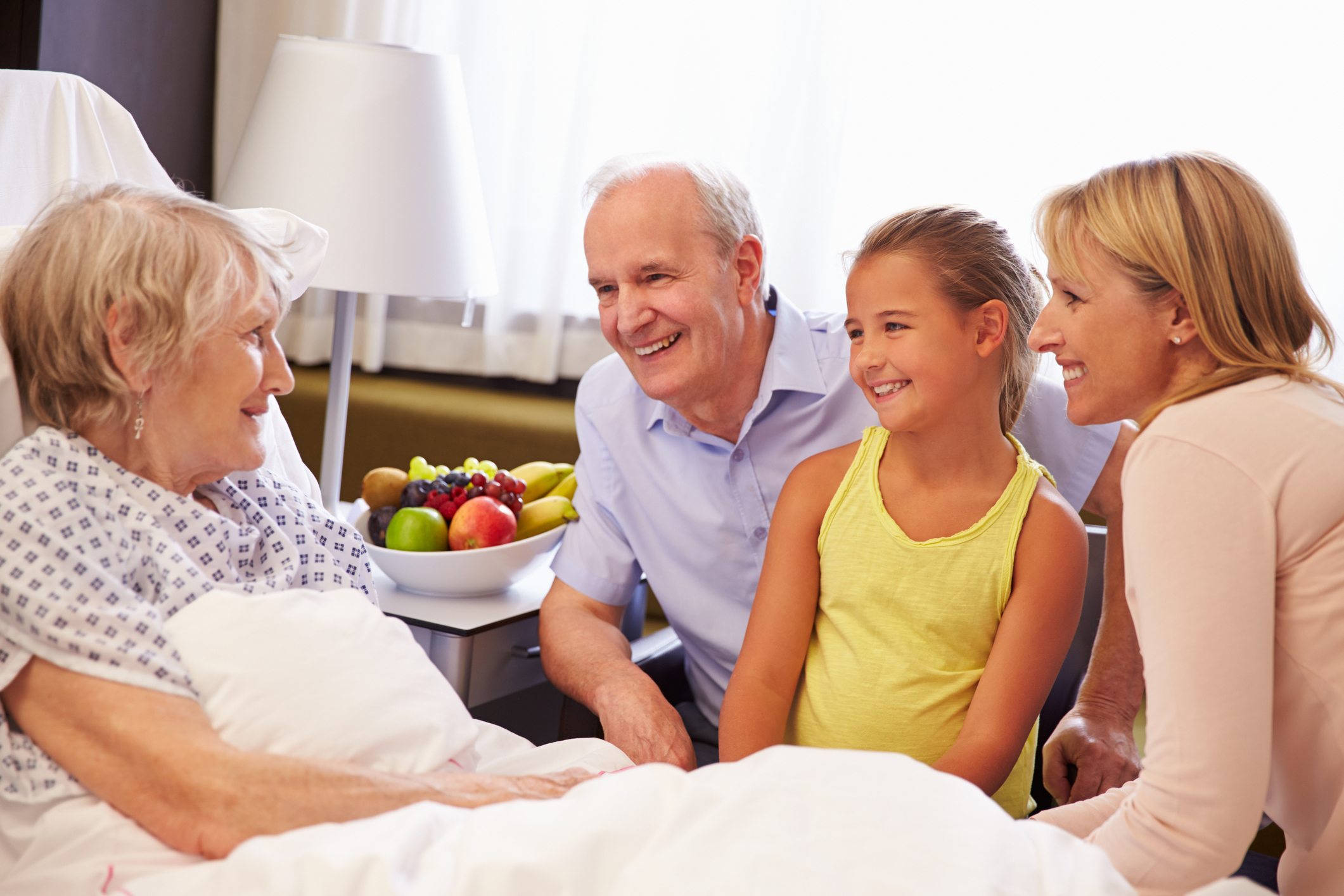 A photo of a family visiting a patient in a hospital bed