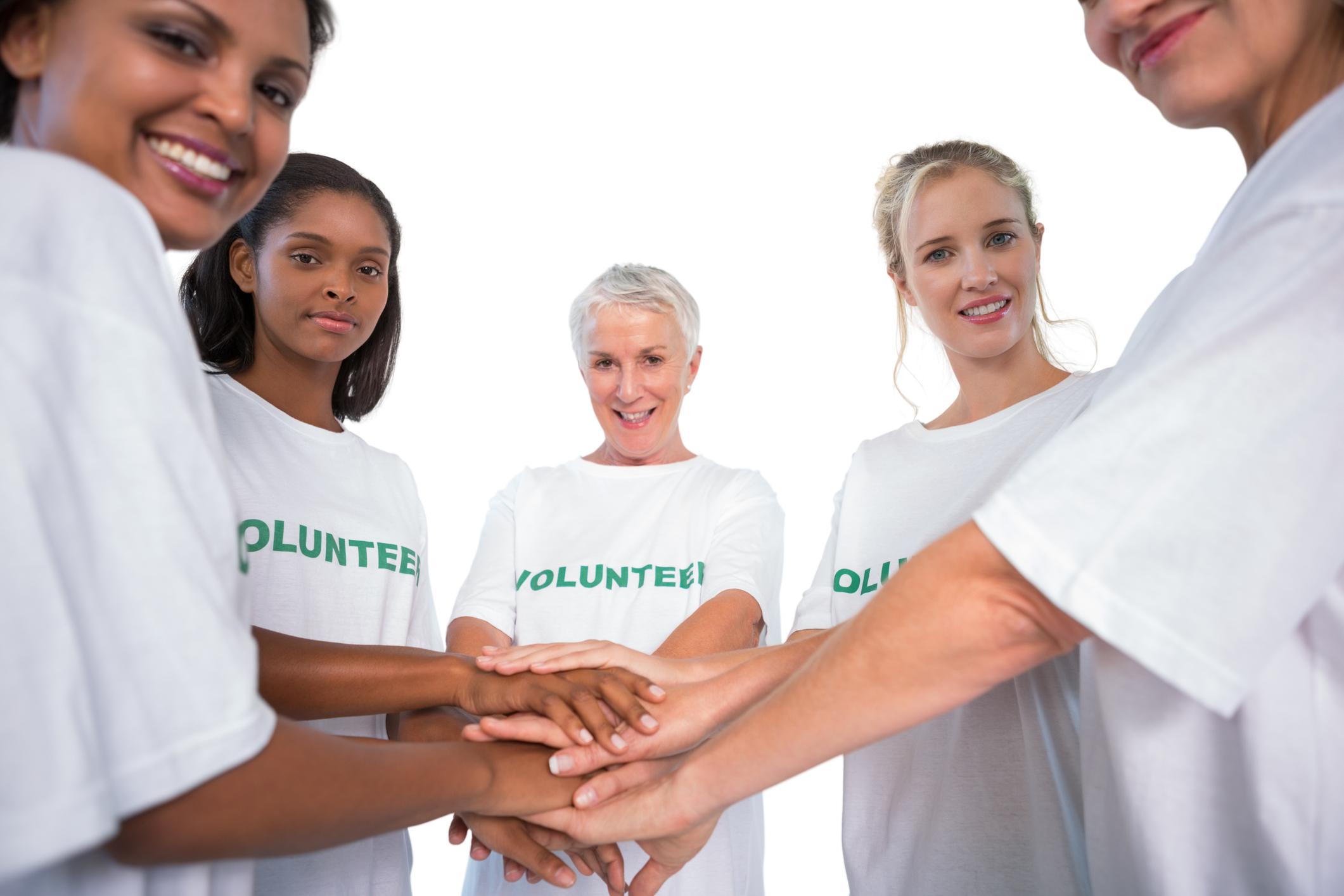 Photo of a team of female volunteers with hands together smiling at camera on white background